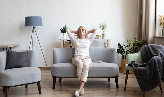 Une femme assise dans son salon pense à la mensualité de son crédit personnel
